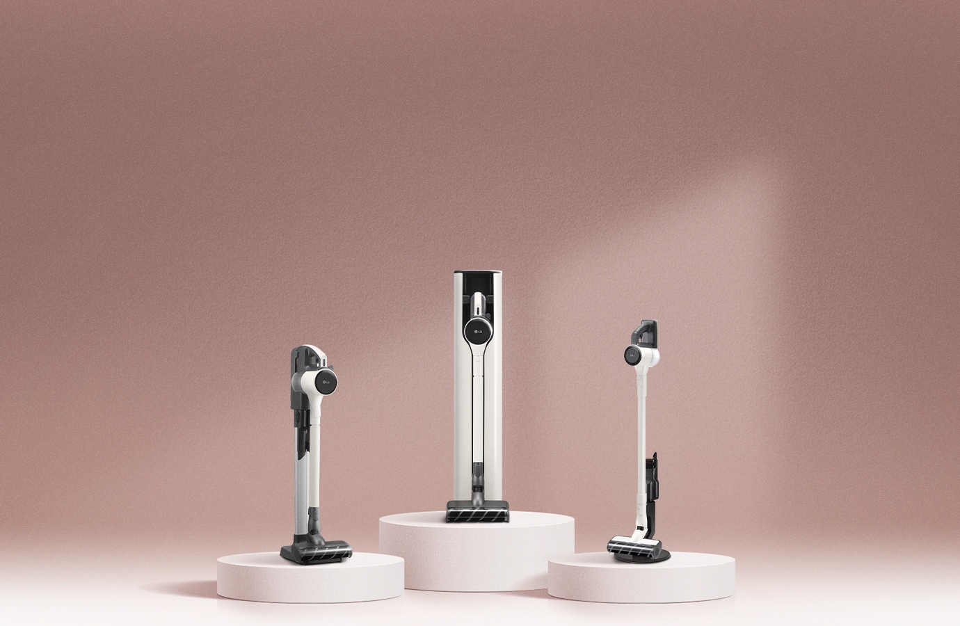 은은한 핑크빛 배경 위에 왼쪽부터 LG 코드제로 A5, LG 코드제로 오브제컬렉션 A7 Core, LG 코드제로 A5 무선청소기가 각각 원형 받침대에 세워진 모습